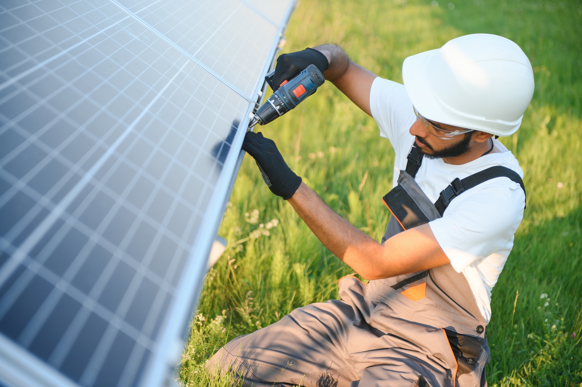 Indian man in uniform working near solar panel.